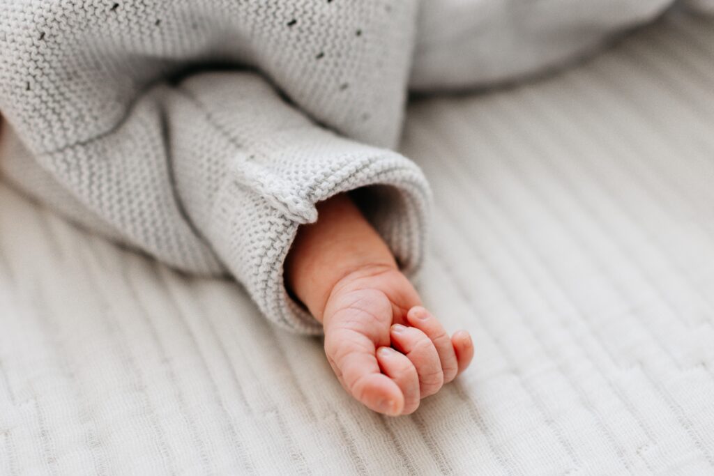 Close up of a newborn babies hand wearing a sweater