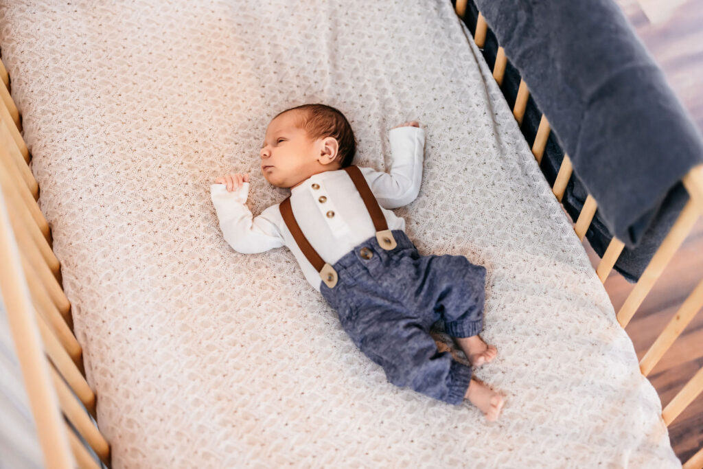 Newborn in a crib wearing suspenders